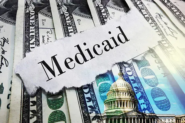 medicaid-newspaper-headline-on-hundred-dollar-bills-with-us-capitol-in-washington-dc